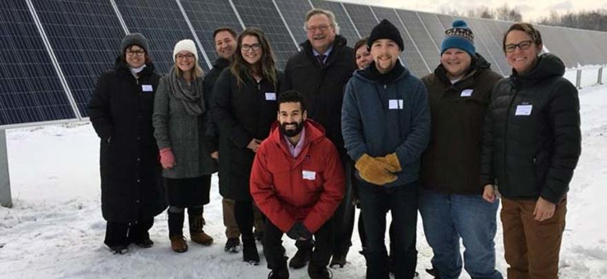 A group of people standing in front of a large set of solar panels.