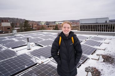 Remi Foust standing on top of HCAMS with solar panels behind her